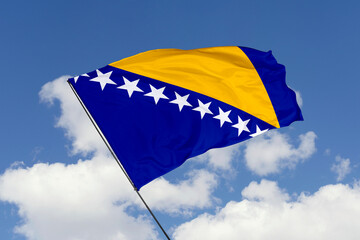 Bosnia and Herzegovina flag isolated on the blue sky background. close up waving flag of Bosnia and Herzegovina. flag symbols of Bosnia and Herzegovina. Concept of Bosnia and Herzegovina.