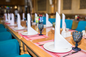 Table setting for a holiday or conference. Dishes on the table, napkins. A beautifully set table for a festive reception of guests.