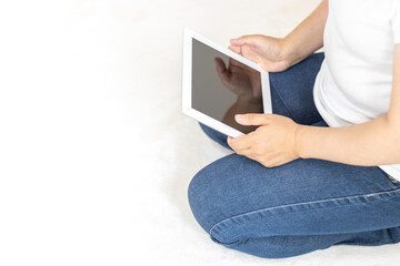 カーペットに座って、タブレット端末を使う女性のイメージ（30代、日本人、顔無し）