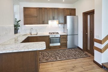 Modern wooden kitchen in scandinavian interior with cooking appliances. Real image