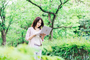 外でパソコンを使う若いビジネスウーマン