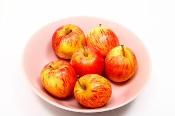 Six ripe eating apples in a bowl and isolated on a white background