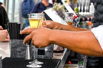 Bar person serving two flute glasses of champagne