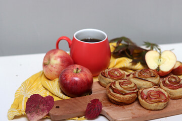 Cup of black tea, red apples, and sweet pastry on a table. Still life food photo. Apple cakes close up.