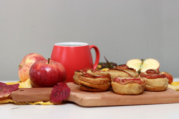 Cup of black tea, red apples, and sweet pastry on a table. Still life food photo. Apple cakes close up.