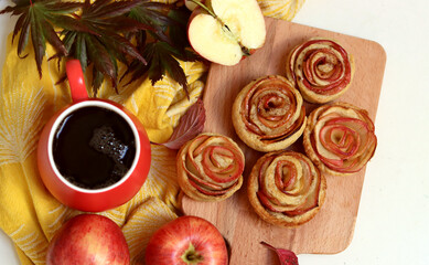 Cup of black tea, red apples, and sweet pastry on a table. Still life food photo. Apple cakes close up.