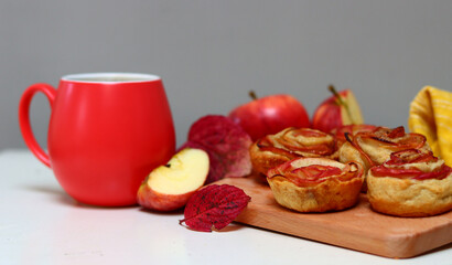 Cup of black tea and apple cupcakes. Close up photo of beautiful dessert tart. Rose shaped Apple Pies on a table. 
