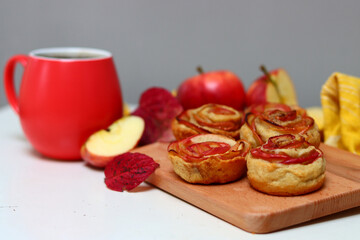 Cup of black tea and apple cupcakes. Close up photo of beautiful dessert tart. Rose shaped Apple Pies on a table. 