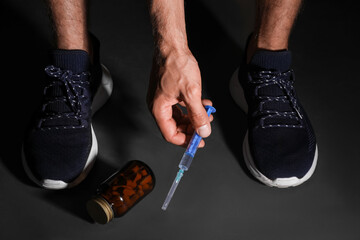 Man taking syringe from black floor, closeup. Doping concept