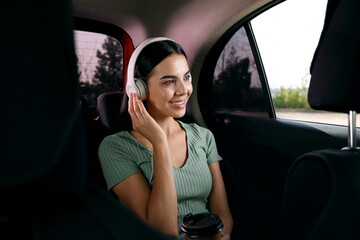 Young woman listening to music in modern taxi