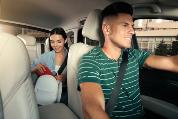 Young woman and taxi driver in modern car