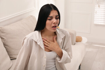 Young woman suffering from breathing problem on sofa at home - obrazy, fototapety, plakaty