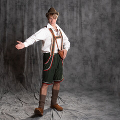 A young man in a national Bavarian suit with shorts on suspenders and a hat.