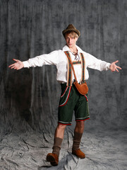 A young man in a national Bavarian suit with shorts on suspenders and a hat. - 463254475