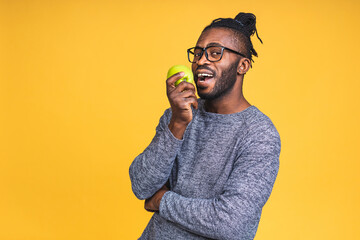 Healthy african american black man holding an apple isolated over yellow background. Diet healthy...
