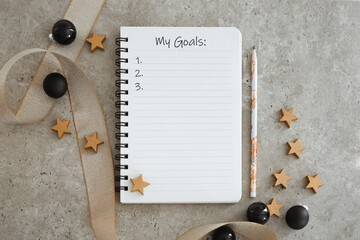 Top view of notebook with Christmas decorations. Goals list for new year. Free space, copy space,...