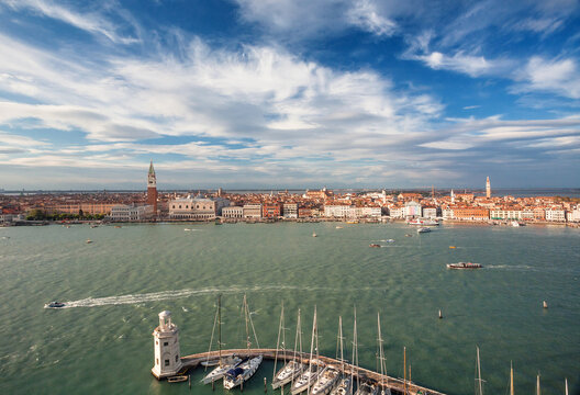 Great Sunny Canals View With City Venice And Riverboats Driving Past Islands Of Lagoon. Blue Sky Over Historical Houses, Churches And Docks Of Ancient Italian City