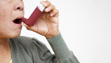 Female senior patient uses brown asthma inhaler for relief asthma. Concept : Health care at home. ...