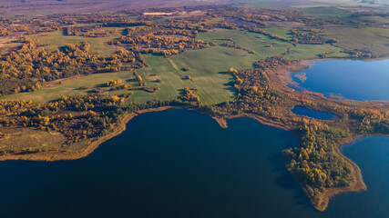 Autumn forest and lake. View from the top. Aerial Photo of an Island in Lake on Sunny Autumn Day.
