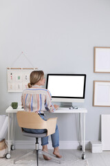 Young woman working on computer at table in room
