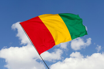 Guinea flag isolated on the blue sky background. close up waving flag of Guinea. flag symbols of Guinea. Concept of Guinea.