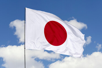 Japan flag isolated on the blue sky background. close up waving flag of Japan. flag symbols of...