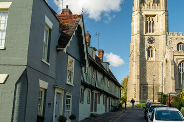 Obraz premium Facade of old traditional terraced cottage brick houses in front of a cathedral at Saffron Walden, England