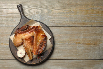 Tasty fried cracklings on wooden table, top view with space for text. Cooked pork lard