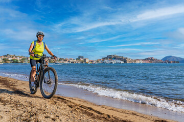 nice woman riding her electric mountain bike at the coastline of mediterranean sea on the Island of...
