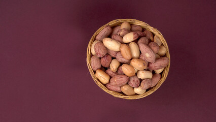 Groundnuts in wooden bowl isolated on plane background, salted roasted peeled nuts, top view