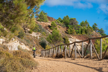 Fototapeta na wymiar nice active woman riding her electric mountain bike in a cactus desert of the abandoned Iron Ore mines of Calamite peninsula on the Island of Elba, Tuscan Archipelago, Tuscany,Italy 