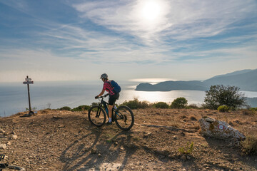 Fototapeta na wymiar nice active woman riding her electric mountain bike in the abandoned Iron Ore mines of Calamite peninsula on the Island of Elba, Tuscan Archipelago, Tuscany,Italy 