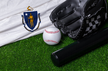 Baseball bat, glove and ball near Massachusetts flag on green grass background