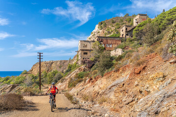 nice active woman riding her electric mountain bike in the abandoned Iron Ore mines of Calamite...