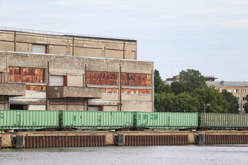 Obraz premium Old brick building with train tracks and cargo train standing nearby. Cargot rain in green color.
