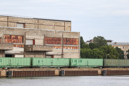 Old brick building with train tracks and cargo train standing nearby. Cargot rain in green color.