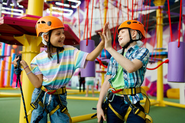 Two children in helmets climb on zip line