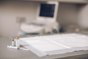 Bottles with vaccines, syringe and clean disposable underpad on table in vet hospital