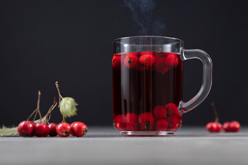 mug of hot tea made from hawthorn berries on a dark background