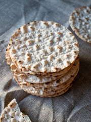 Thin round crispbread baked with wheat, rye and barley in stack on textile background