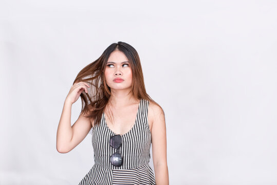 An annoyed or disgusted young lady flings her hair while looking away. Wearing a striped sleeveless blouse. Isolated on a white background.