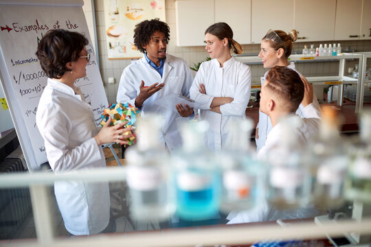 Young colleagues discuss a chemistry lesson in the university laboratory. Science, chemistry, lab, people - Powered by Adobe