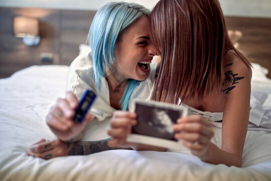 Lesbian couple on bed sharing happiness because of pregnant love partner