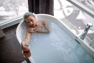 Portrait of a hot punk girl taking a bath; Hedonistic lifestyle