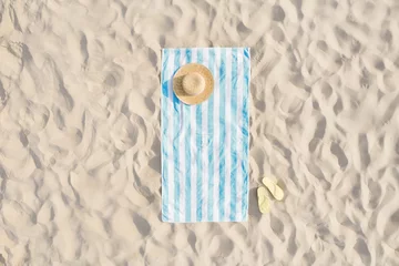 Fototapeten Strand Striped beach towel, straw hat and flip flops on sand, aerial view  © New Africa