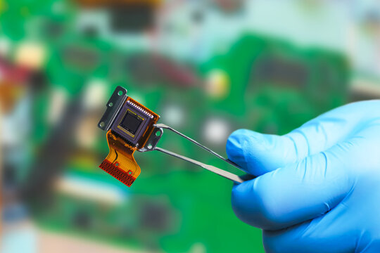 CCD sensor of a digital camera, man holding Silicon CCD matrix with tweezers in the science lab