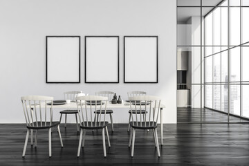 Three frames on white wall of dining room with black wood floor