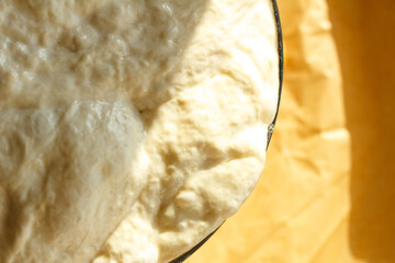 Ciabatta yeast dough rests and rises in a glass bowl under a towel