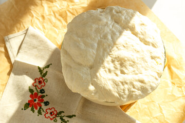 Ciabatta yeast dough rests and rises in a glass bowl under a towel
