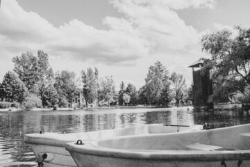 Reflejo Lago con barcas arboles y cielo azul con nubes blanco y negro